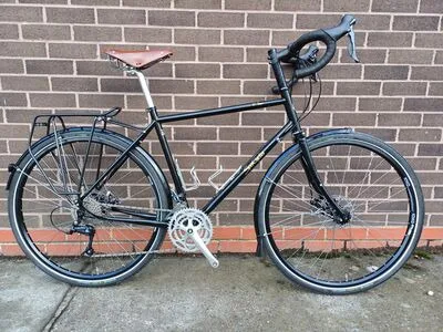 Black Spa Cycles D'Tour 725 touring bike with rack and leather saddle against a brick wall